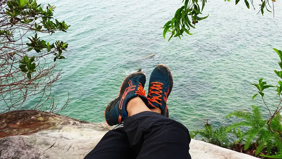 View of a man wearing an Asics shoes at the rocky coastline