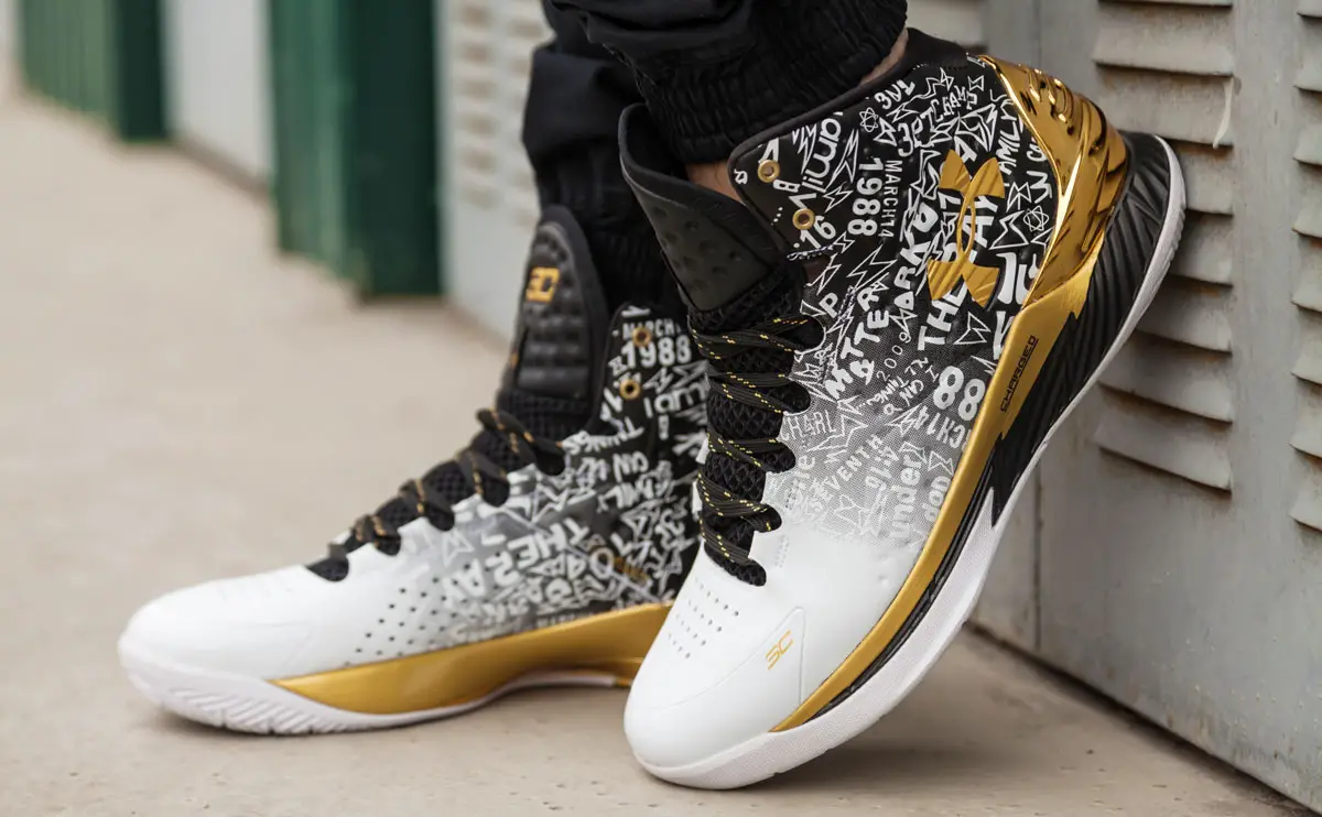 A black and white with a gold color Under Armour shoes